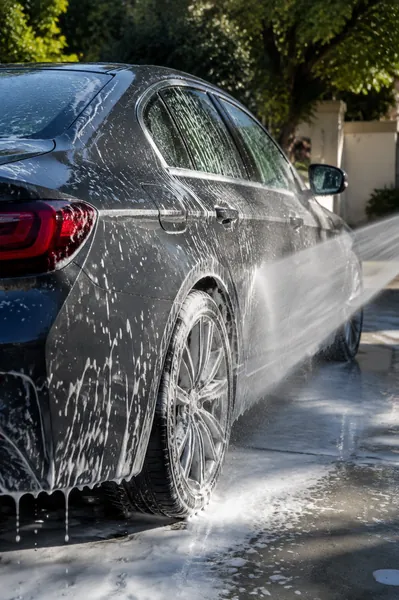 White foam on a dark sedan during an exterior wash